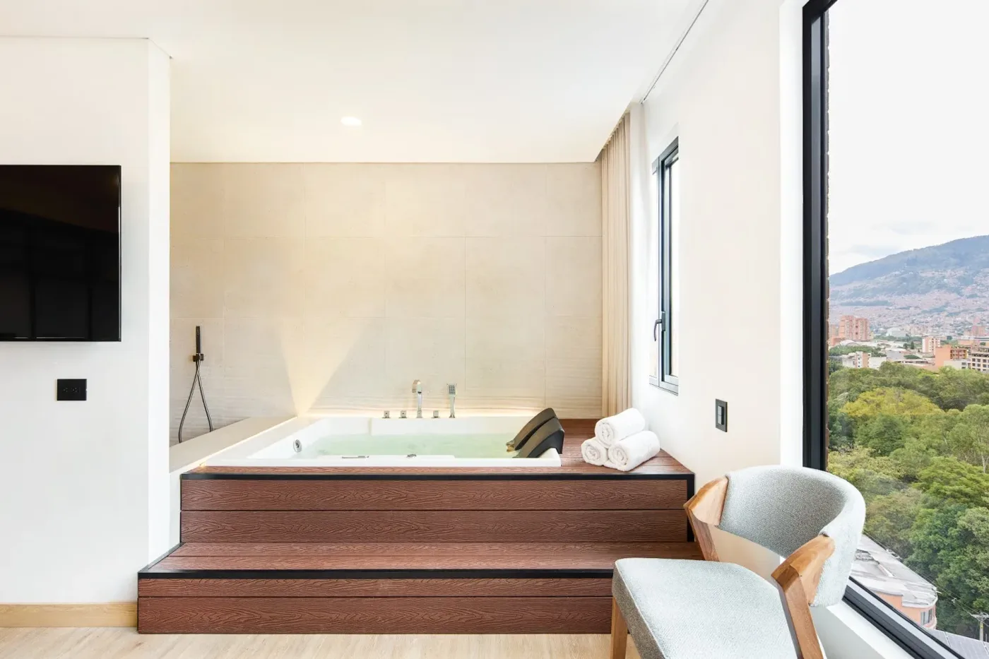 Jacuzzi sobre tarima de madera junto a un ventanal con vista verde, en la Suite Exclusiva
