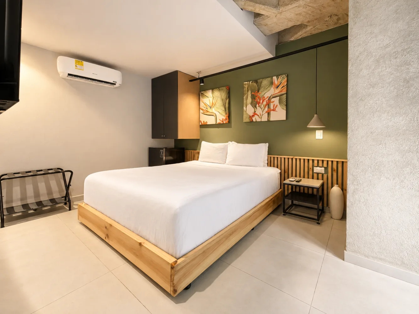 Suite Ejecutiva: cama queen con base de madera y cuadros de heliconias