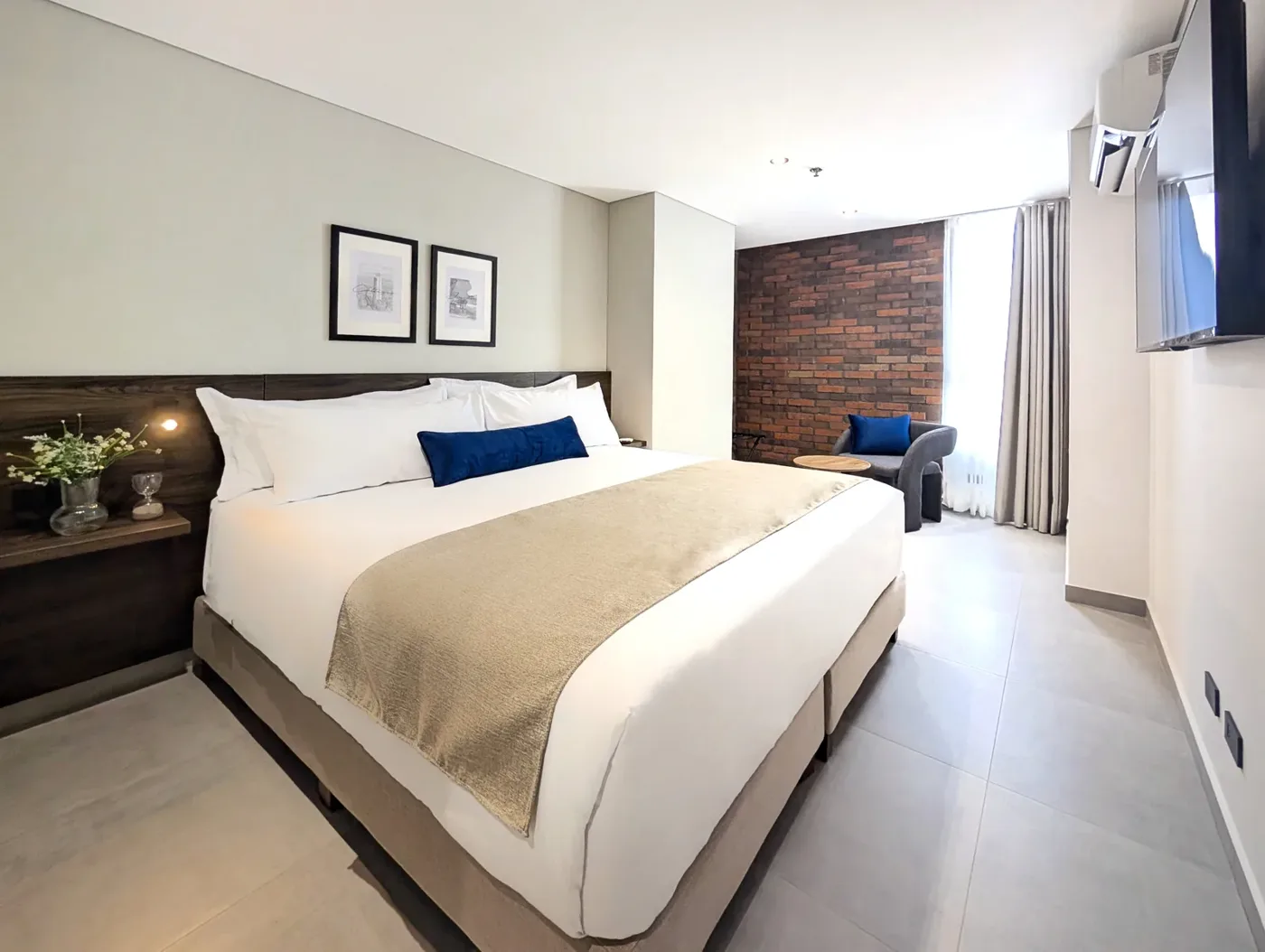 Dormitorio de la suite Family con cama king y muro de ladrillo